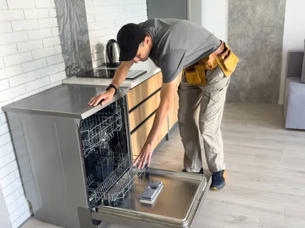 Man repairing a dishwasher in kitchen