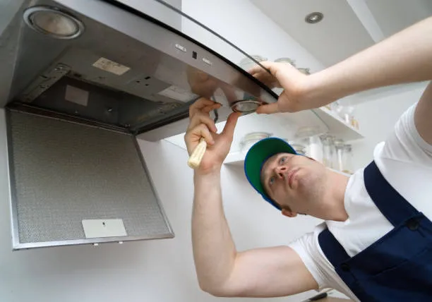 An expert technician providing electric stove repair dubai by inspecting a built-in oven unit in a modern kitchen.