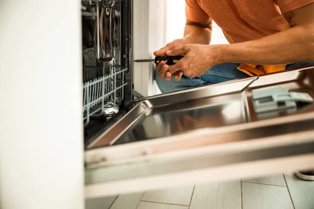 A skilled technician using a screwdriver to fix a door latch during a high-quality dishwasher repair Abu Dhabi service call.