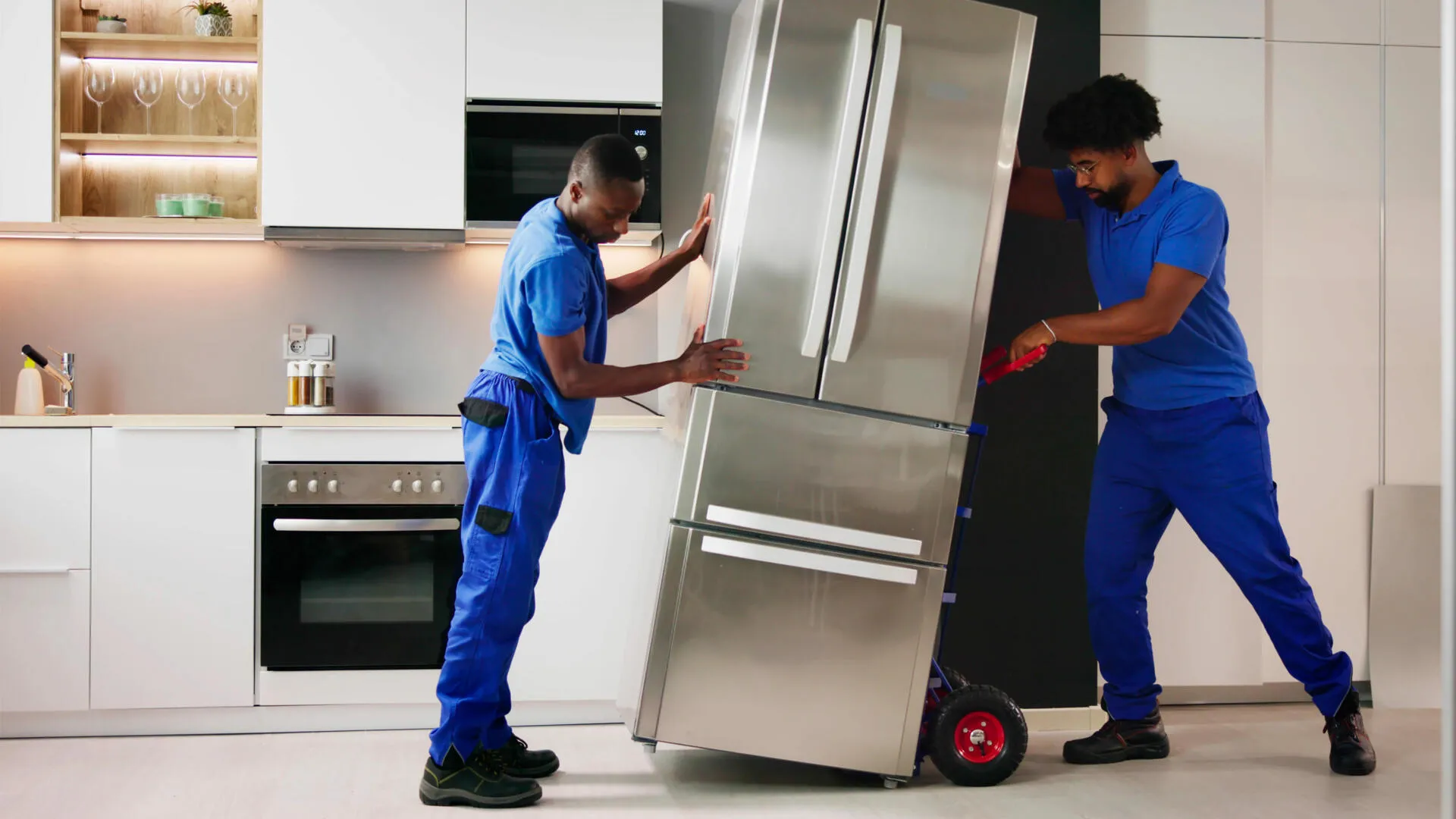 Skilled technician using a screwdriver to perform a technical inspection of a refrigerator’s rear cooling unit and electrical wiring.
