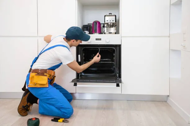 A 24x7 Service specialist using precision tools to fix the internal wiring and thermostat for high-quality oven repair services Ajman.