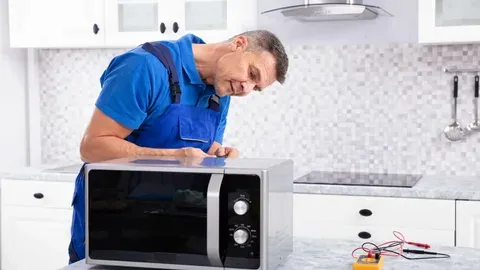 A person repairing oven in blue shirt
