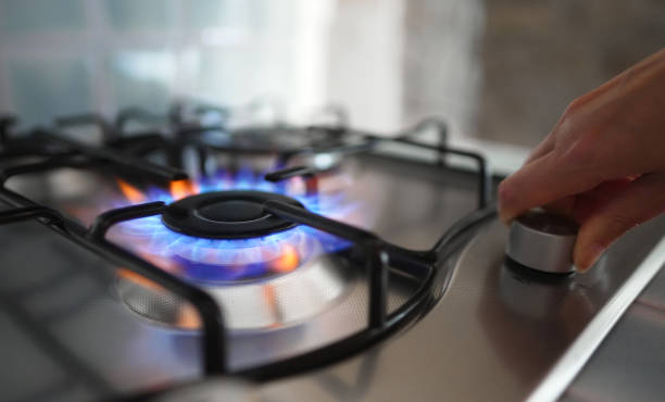 Woman turning on the gas burner on the stove.