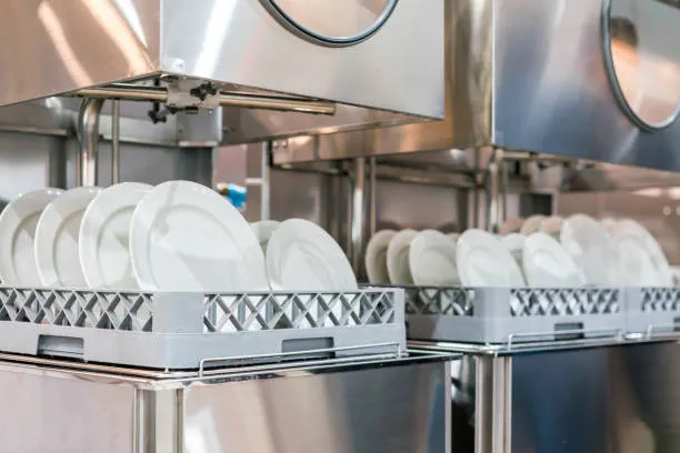 An interior view of dirty plates and glassware being loaded into a dishwasher, used to illustrate how proper loading saves water and energy for 24X7 Service UAE customers.