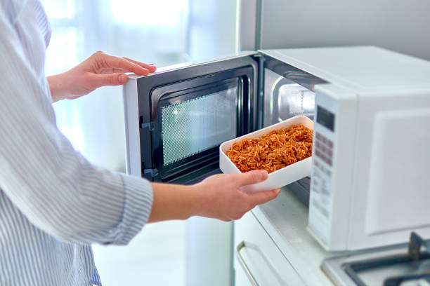 Warming up a container of food in the modern microwave oven for snack lunch at home