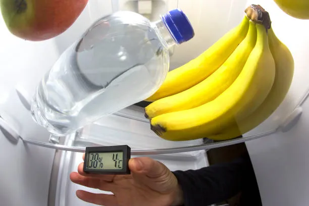 A close-up view of a refrigerator's interior with a digital thermometer displaying 4°C, illustrating the ideal cooling setting for food safety in Dubai.